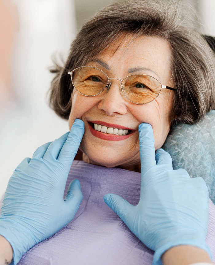 Dentist with blue gloves looking at senior woman's smile