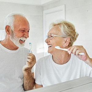 Senior couple smiling while brushing their teeth