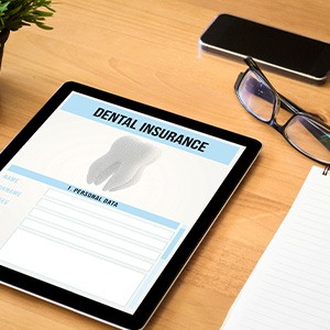 Dental insurance form on tablet next to desk supplies