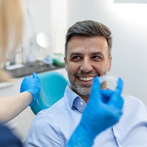 Patient smiling at dentist holding clear aligner