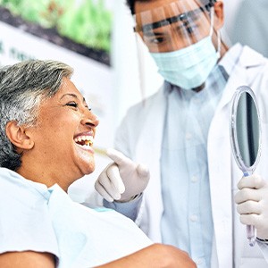 Dentist pointing to woman's smile in treatment chair