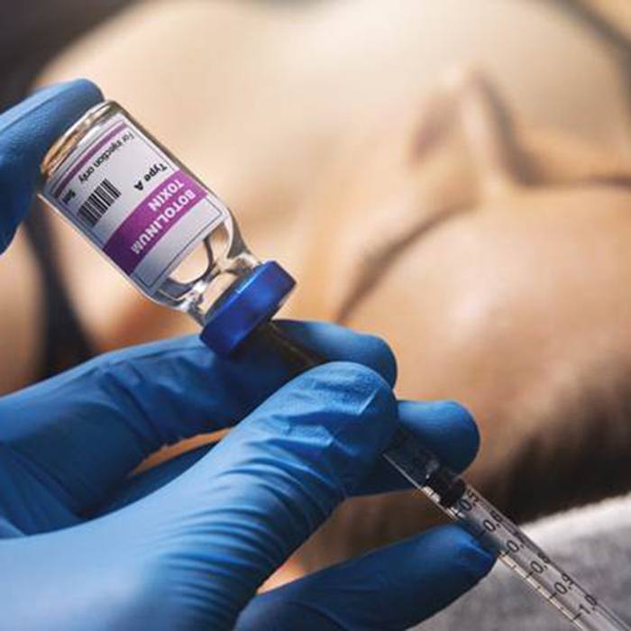 Gloved hand measuring botulinum toxin into needle