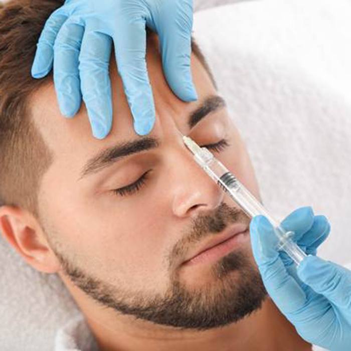 Man receiving facial injection between eyebrows