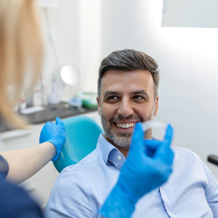 Man smiling at dentist holding Invisalign