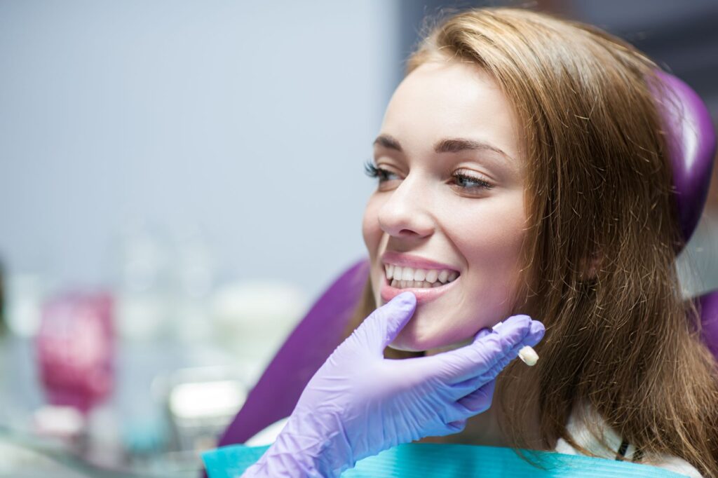 Dentist's gloved hand touching woman's chin to examine teeth