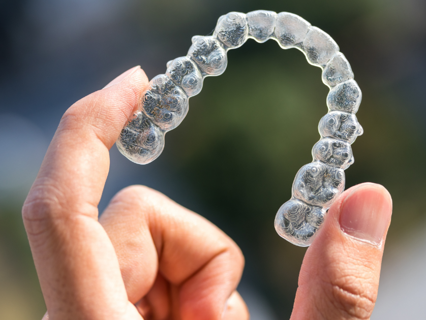 Hand holding clear aligner