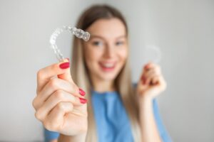 Woman holding Invisalign clear aligner. 